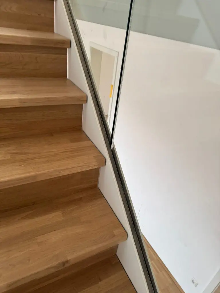 Treppenhausreinigung in Ulm gereinigte Holztreppe mit Glasgeländer und sauberen Stufen