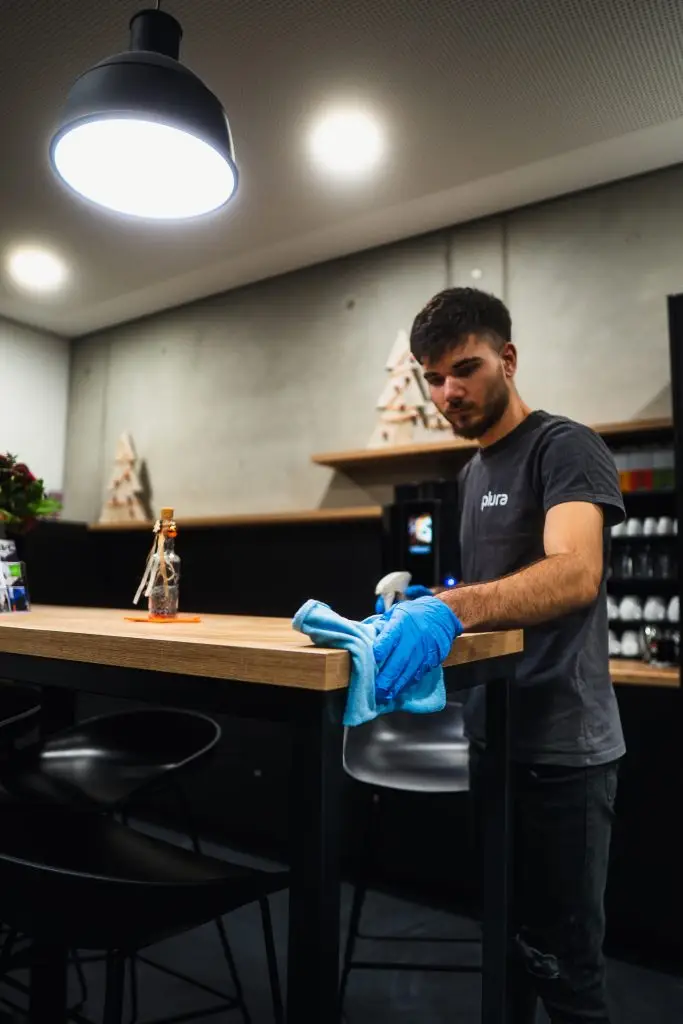 Büroreinigung in Ulm: Plura-Mitarbeiter reinigt die Tischfläche im Unternehmen