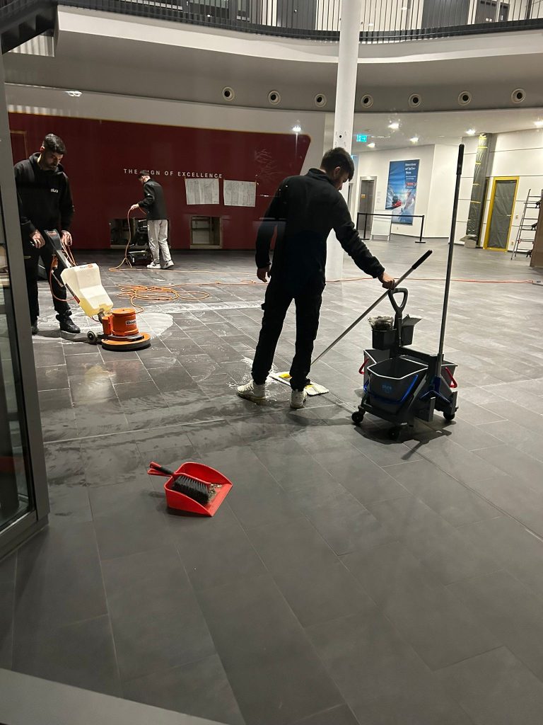 Team von Plura Gebäudereinigung Ulm bei der Baureinigung in Ulm mit maschineller Bodenreinigung und Feuchtwischen in einer großen Eingangshalle